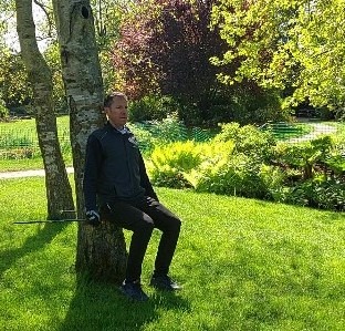 Exercice de la chaise en marche nordique, dos contre un arbre, jambes formant un angle droit